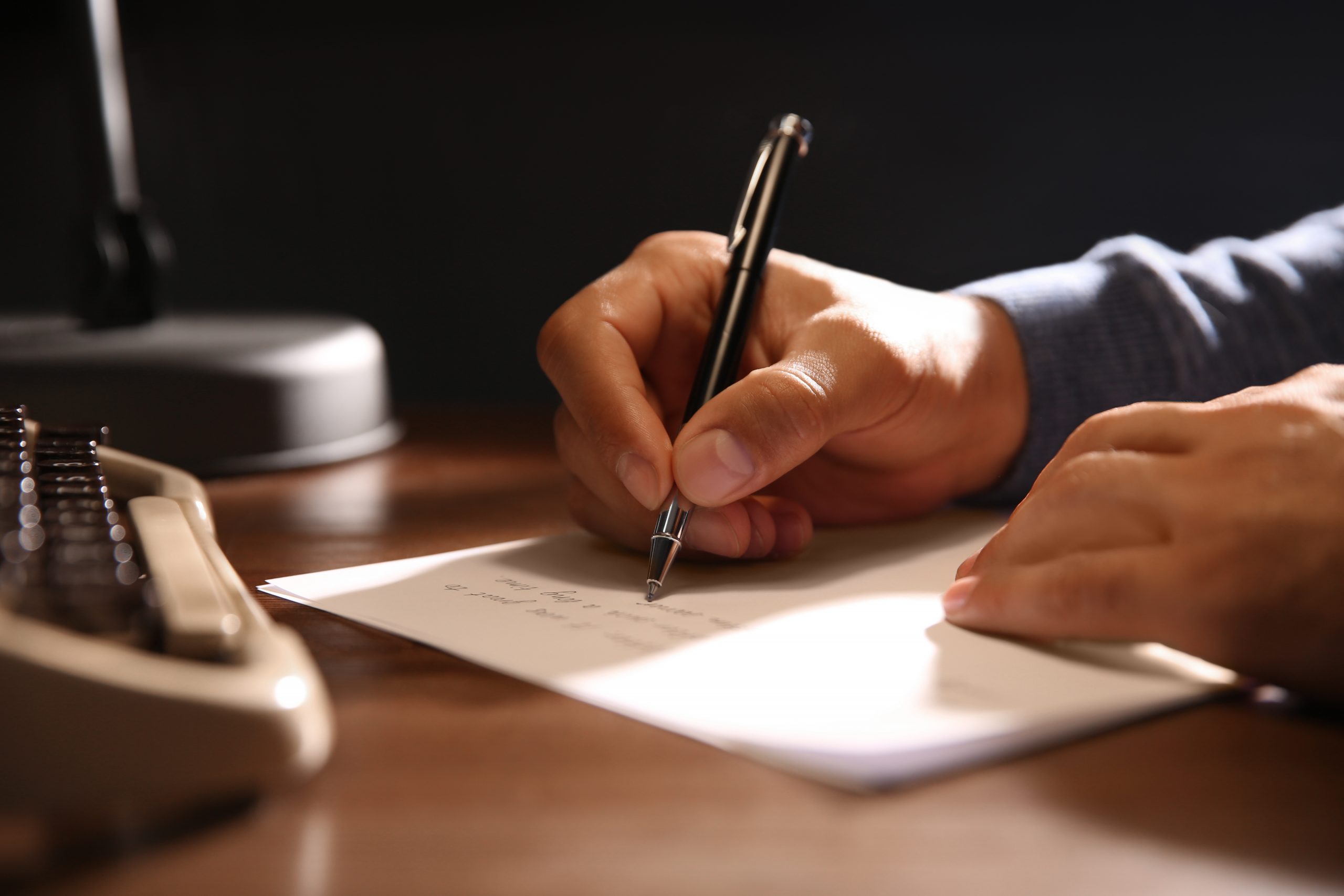 Man writing letter at wooden table indoors, closeup bipolaire stoornis depressie